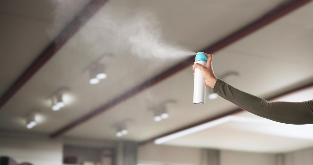 femeie care pulverizeaza odorizant profesional in sala de sport